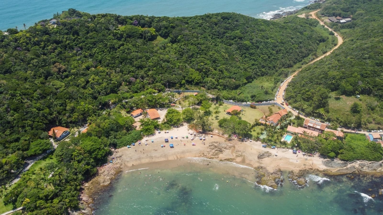 Vista aérea de uma praia de Penha SC com casas cercadas de mata atlântica